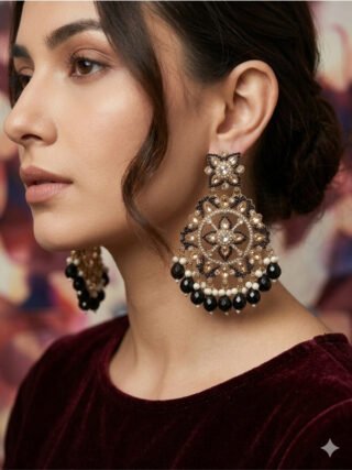 Melegant by LC heavy black and gold Kundan Chandbali statement earrings featuring intricate floral motifs, white pearl clusters, and dangling black onyx briolette drops displayed on a metal stand
