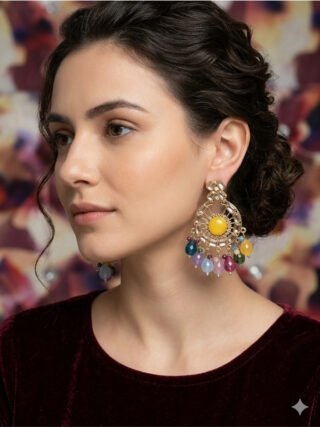 Model wearing Melegant by LC modern gold chandbali earrings featuring a bright yellow round center stone, crystal sunburst framing, and multi-color hanging gemstone beads against a dark maroon velvet top