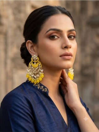 Sunshine yellow Kundan and pearl chandbali earrings displayed on a stand with Melegant the Fashion Studio branding tag for online and in-store shopping in Indirapuram Ghaziabad.