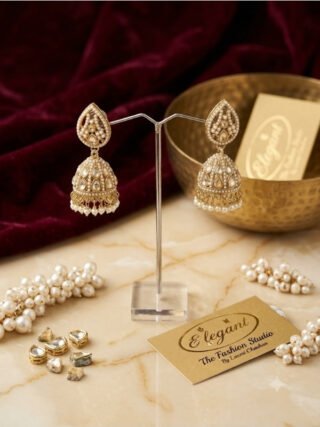 Traditional gold Kundan and pearl jhumka earrings displayed on a stand with Melegant the Fashion Studio branding card for online and in-store shopping in Indirapuram Ghaziabad.