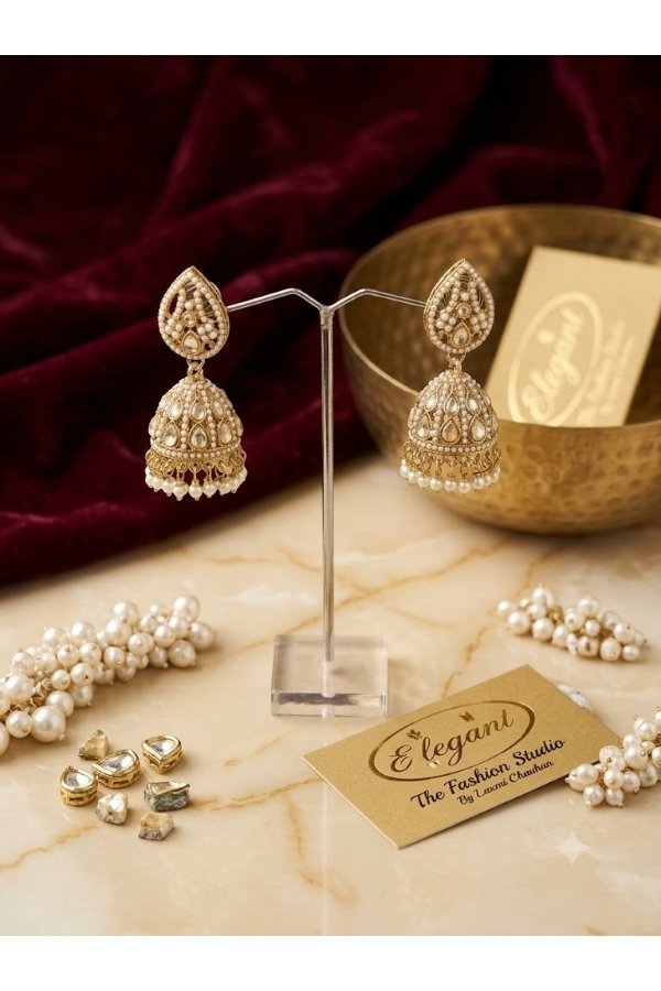 Traditional gold Kundan and pearl jhumka earrings displayed on a stand with Melegant the Fashion Studio branding card for online and in-store shopping in Indirapuram Ghaziabad.